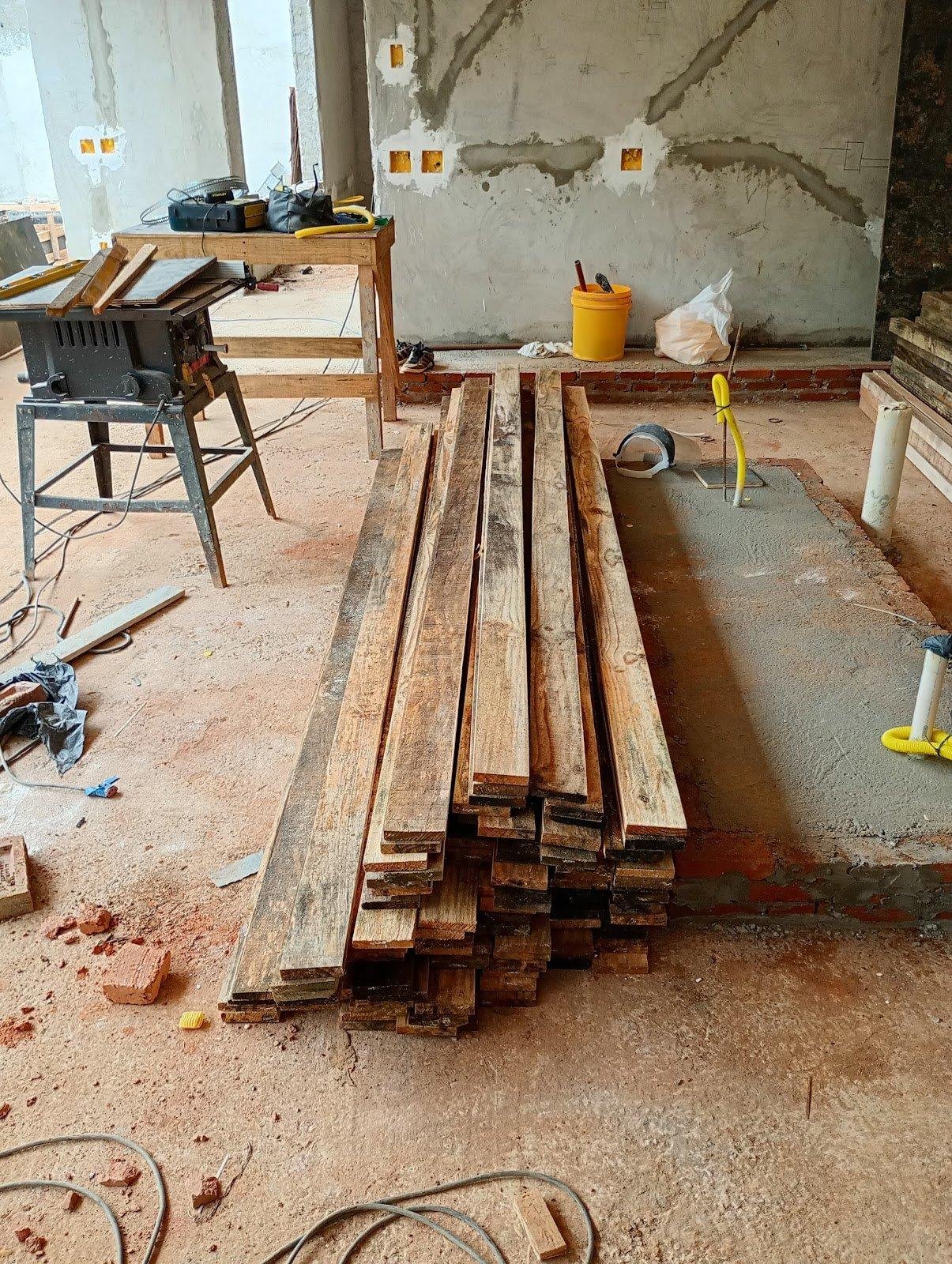 Madeiras serradas em uma obra em andamento com ferramentas ao lado.