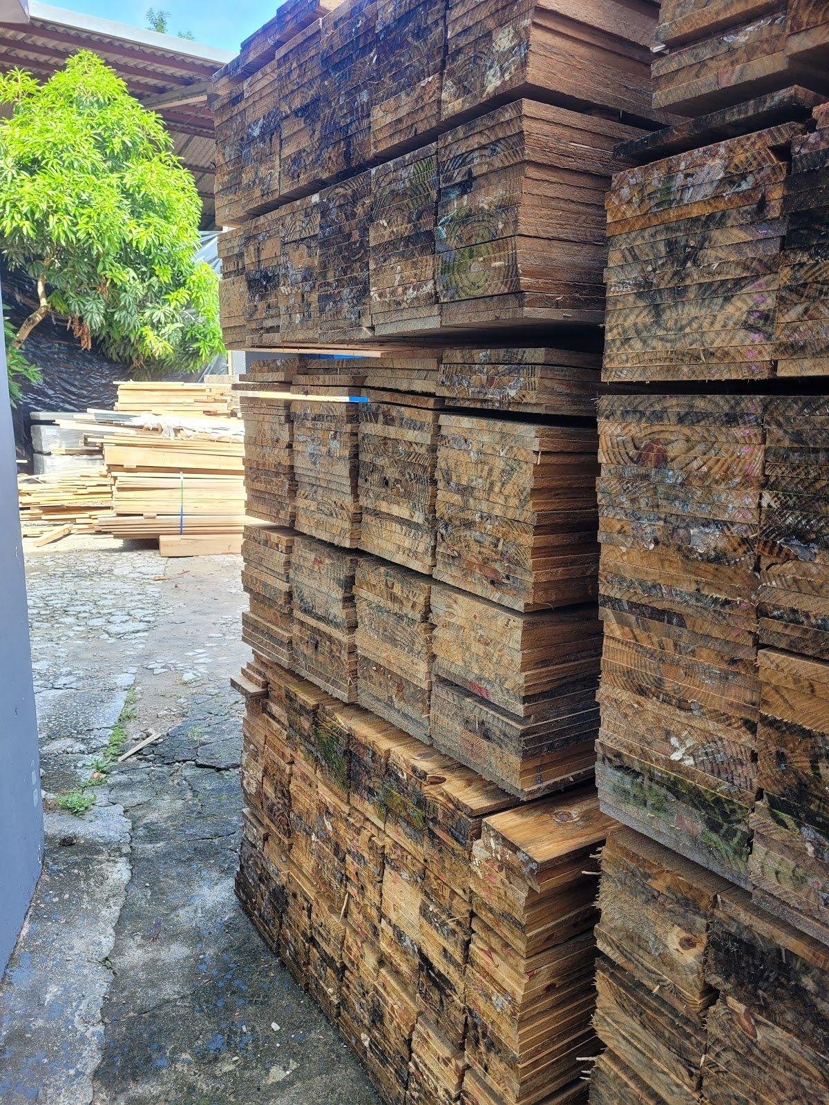 Detalhe de pilhas de tábuas de madeira em ambiente externo.