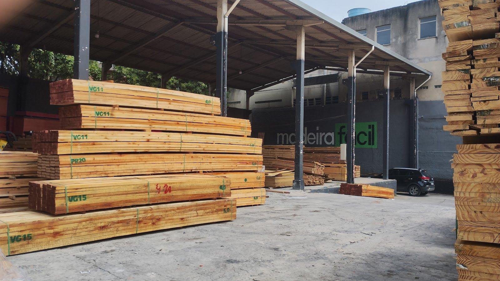 Uma visão ampla do pátio da madeireira com pilhas organizadas de madeira serrada.